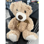 Plush teddy bear with a ribbon bow sitting on a desk