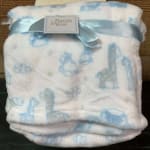 Folded baby blanket with a blue ribbon and tag