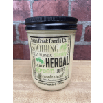 A jar candle with a black lid and herb-themed label