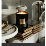 Lit black candle in a glass jar on stacked books