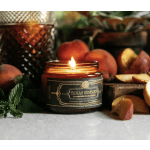Lit candle in a glass jar surrounded by peaches and fruit slices