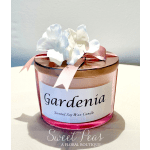 Gardenia scented candle in a pink glass jar with ribbon and white flowers on top