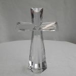 Clear glass cross standing on a white surface