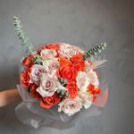 Bouquet of coral, blush, and white roses with eucalyptus in translucent wrap