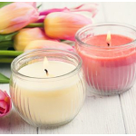 Two scented candles in glass jars beside pink and yellow tulips