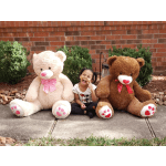 Two large teddy bears sit beside a smiling child outdoors.