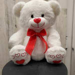White teddy bear with a red bow and heart details