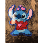 Glittery Stitch character cutout with pink hearts on a wooden surface