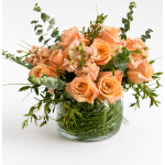Peach roses and small pink flowers in a clear glass vase