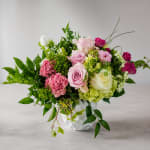 Mixed pink, white, and green floral arrangement in a white vase