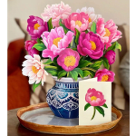 Pink and white flowers in a blue patterned vase with a card