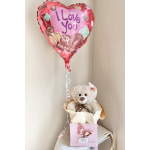 Heart-shaped "I Love You" balloon above a teddy bear gift box