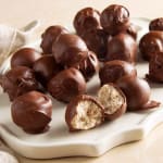 Chocolate-covered truffles on a white serving tray, one cut open