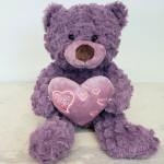 Purple teddy bear holding a pink heart pillow