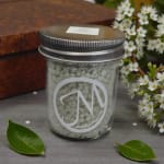 Glass jar filled with white pellets beside small white flowers
