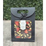 Black gift box with a window showing strawberry and pistachio chocolate bars