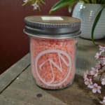 Jar of pink wax beads with a metal lid and logo