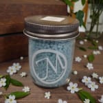 Glass jar filled with blue beads and a metal lid, surrounded by small white flowers