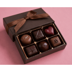 Box of assorted chocolates with a ribbon on a pink background
