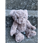 Small plush teddy bear sitting on a stone surface