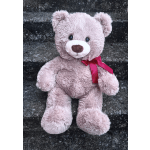 Pink teddy bear with a red ribbon sitting on stone steps