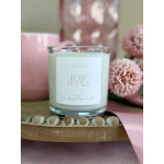 Rose-scented white candle in a clear glass jar with pink mug, flowers, and ribbon on a wooden tray