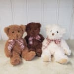 Three teddy bears with plaid bows sitting side by side