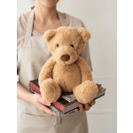 Person holding a teddy bear on top of a stack of books