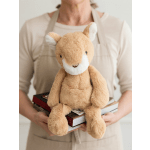 Person holding a plush fox toy on top of a stack of books