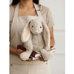 Person holding a plush bunny toy on top of a stack of books