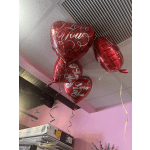 Red heart-shaped balloons with "I Love You" text hanging indoors.