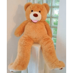 Large orange teddy bear sitting on a white pedestal by a window