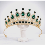 Gold tiara with green gemstones on a white pedestal