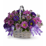 Purple and pink daisy bouquet in a white wicker basket with ribbon bows