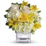 Yellow and white flower arrangement in a clear square vase