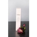 Rose hand cream box standing upright beside a single dark pink flower.