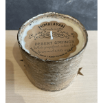A handmade candle in a textured metallic container with a paper label