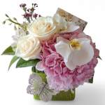 Pink and white floral arrangement in a green wrapped container with a butterfly accent.