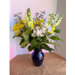 Mixed bouquet of yellow, blue, and pale pink flowers in a dark vase