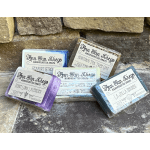 Four wrapped bars of handcrafted soap on a stone surface