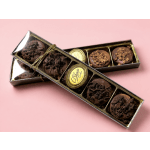 Boxes of chocolate-covered cookies tied with a gold ribbon on a pink background