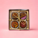 Box of four decorated chocolates tied with a gold ribbon