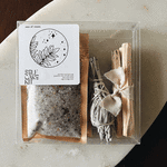 Self-care kit in a clear box with bath soak and bundled sage sticks