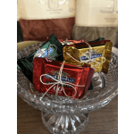 Assorted Ghirardelli chocolate squares tied with string in a glass bowl