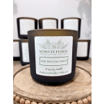 Black jar candle labeled "The Potting Shed" on a wooden tray