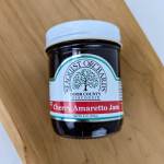 Jar of cherry amaretto jam with a white lid on a wooden surface