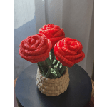 Three red rose-shaped flowers in a woven basket container