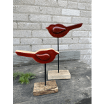 Two red bird sculptures on wooden bases against a brick wall.