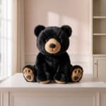 Black plush teddy bear sitting on a white table