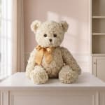 Cream teddy bear with a gold ribbon sitting on a table